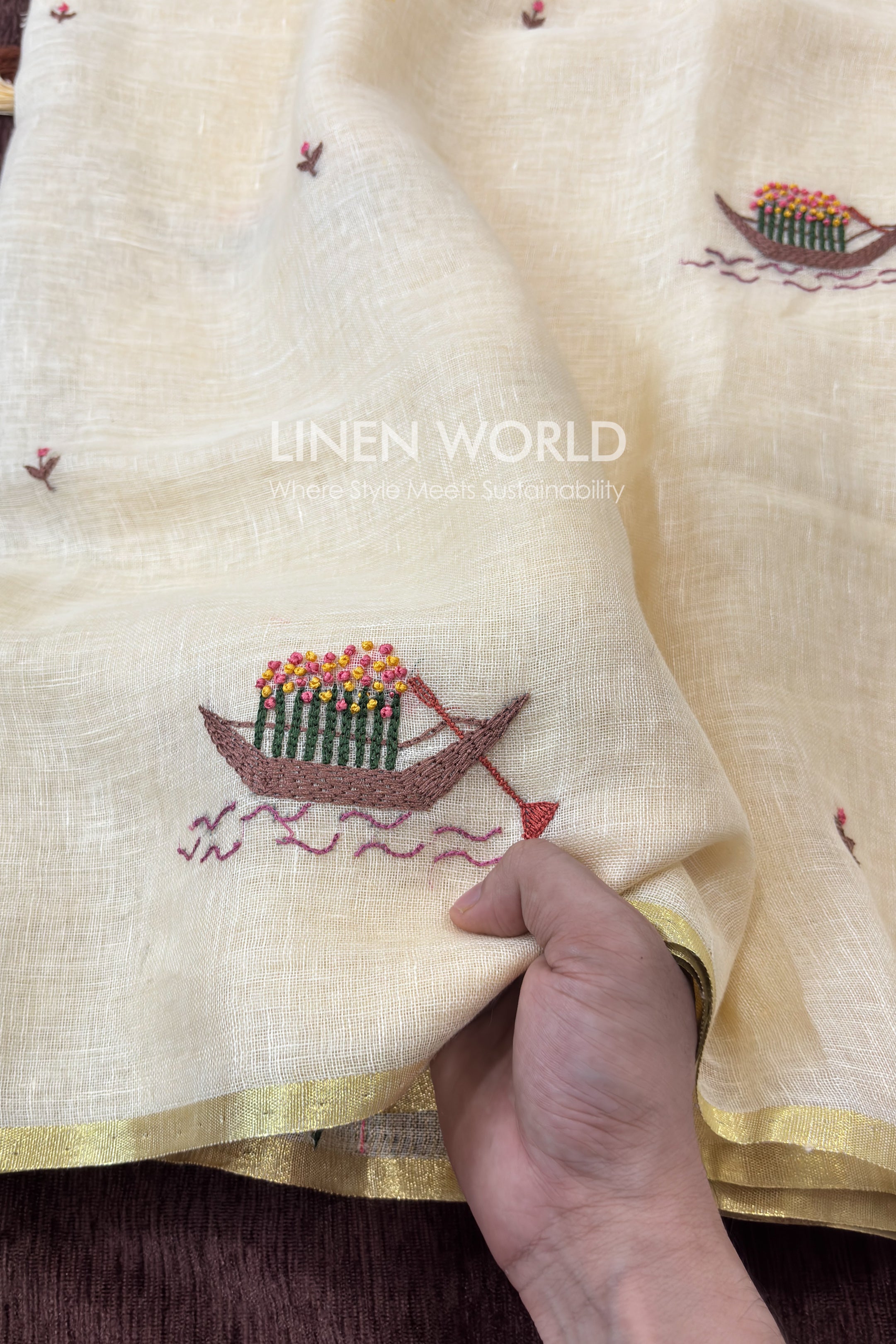 Close-up of hand embroidered boat filled with pink and yellow flowers on cream linen saree by linen world