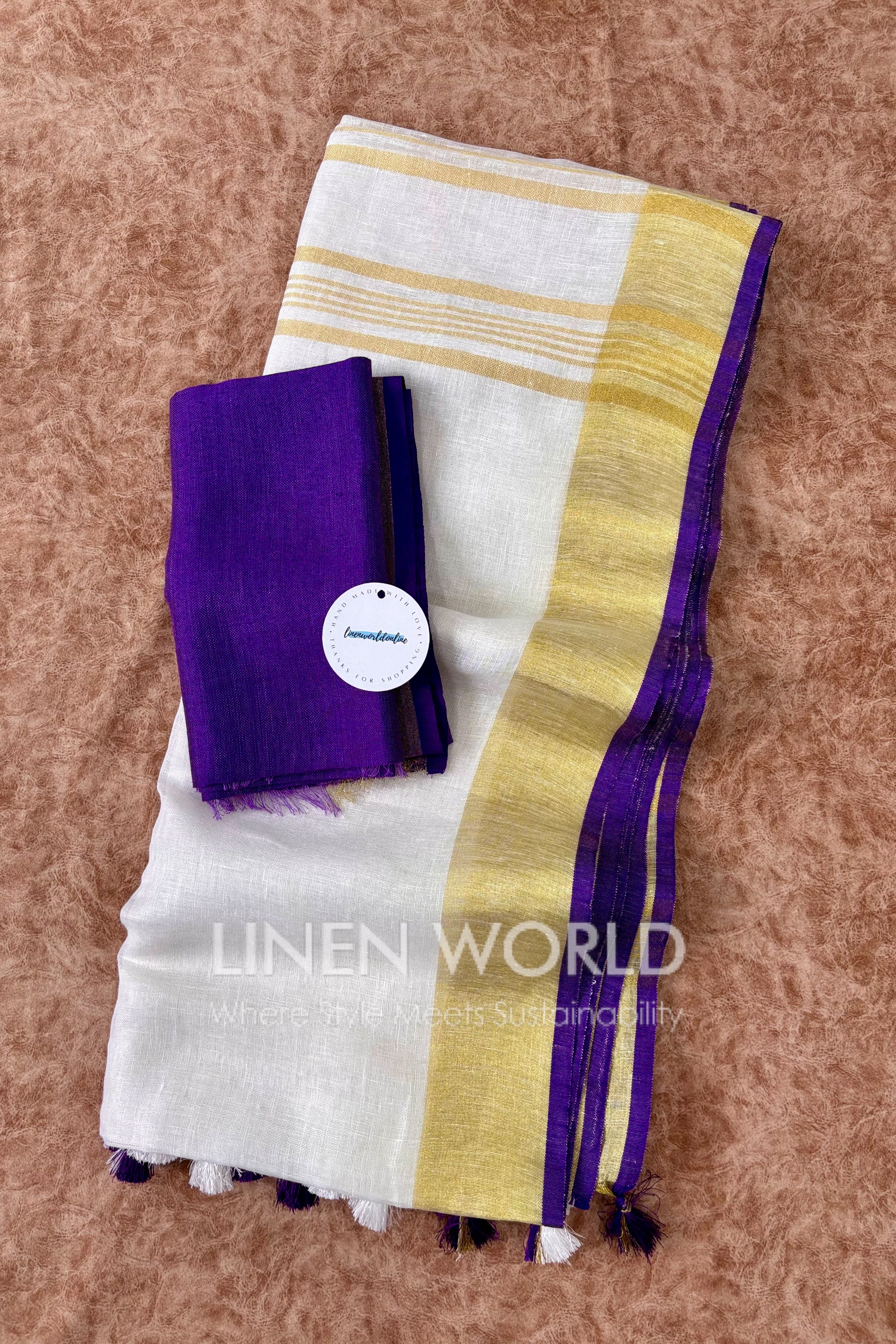 Purple and white linen saree with gold zari border, branded 'Linen World'.