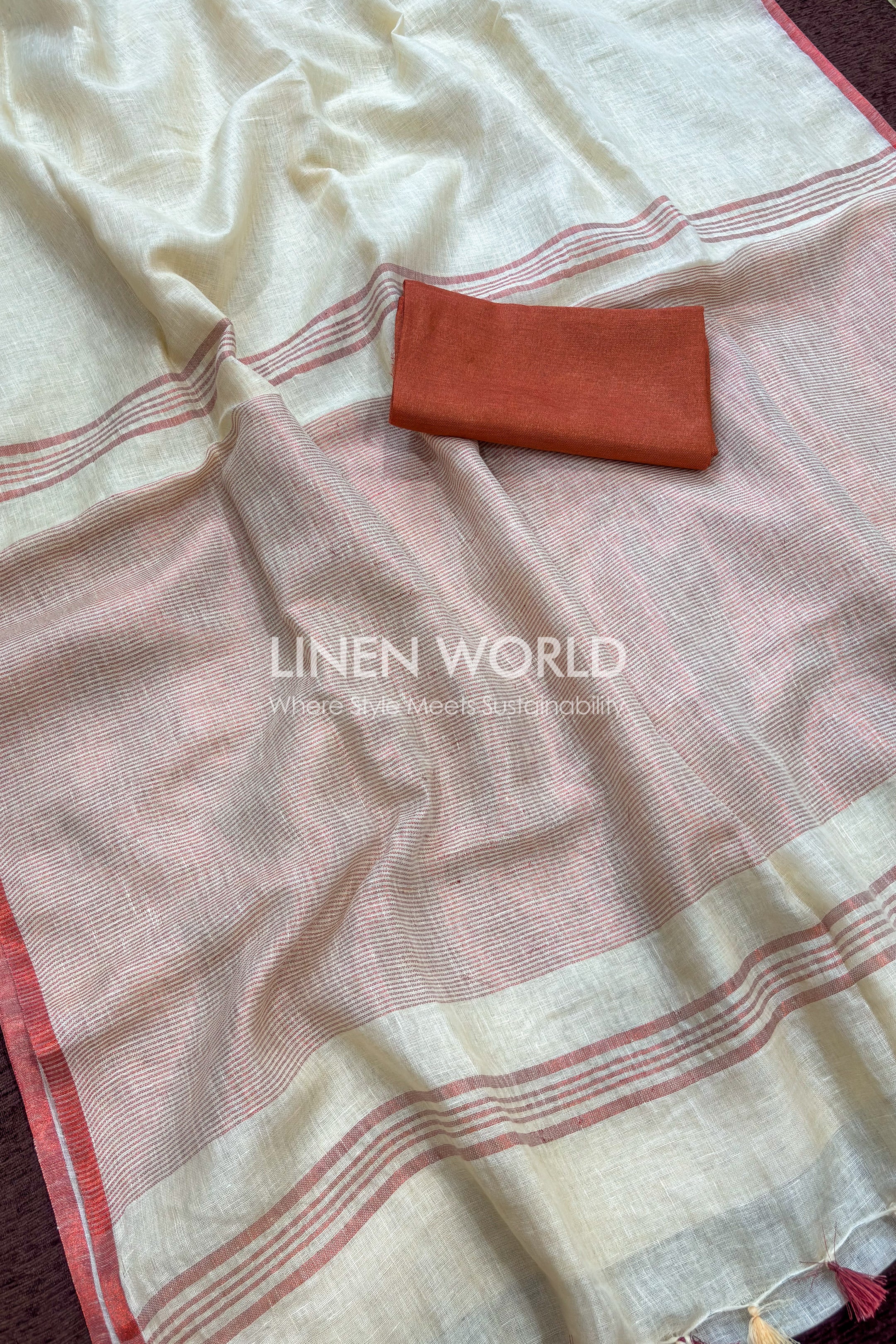 Cream linen saree with rose gold border laid flat, paired with contrast blouse piece by linen world