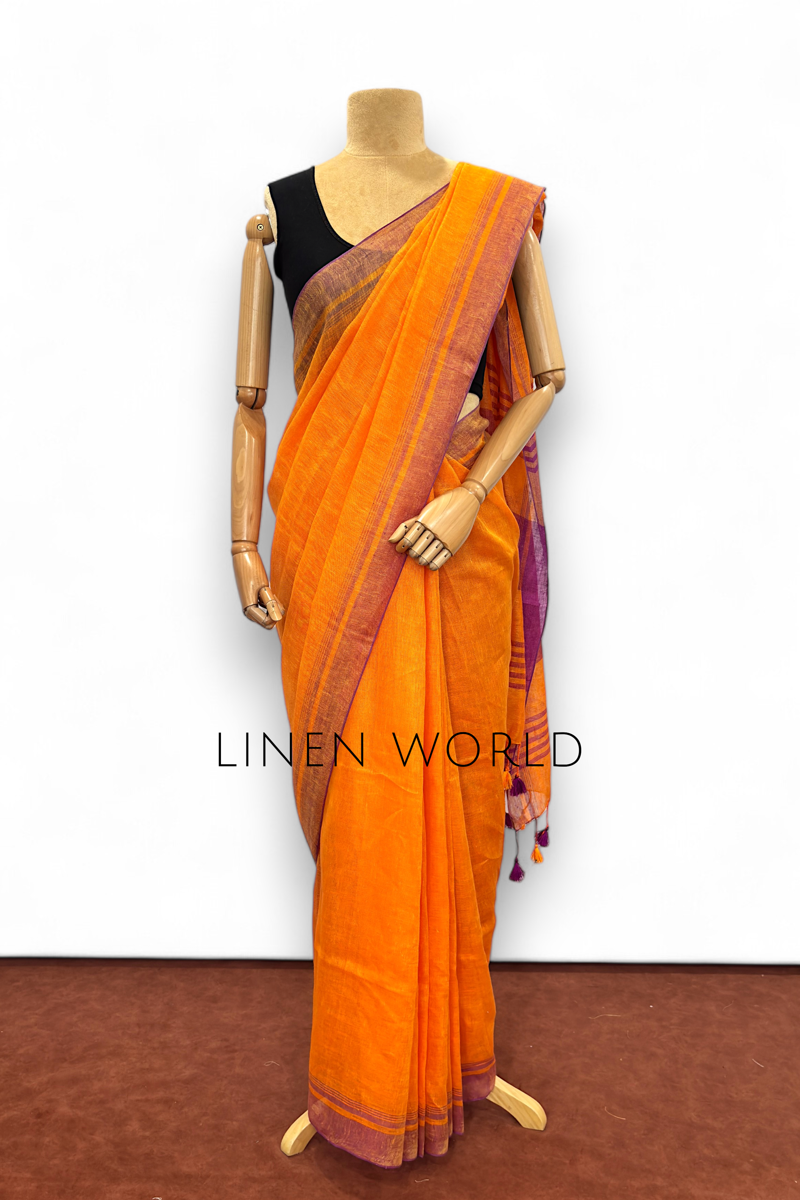 Office and daily wear orange linen saree with tassels branded 'Linen World'.